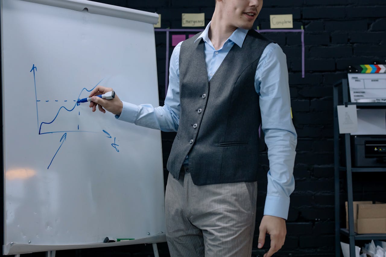 A businessman drawing a graph on a whiteboard during a presentation in an office environment.